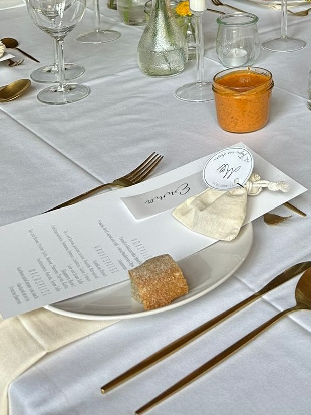 Gedeckter Tisch für Hochzeit mit hochwertigem Geschirr, goldenes Besteck und Leinenservietten